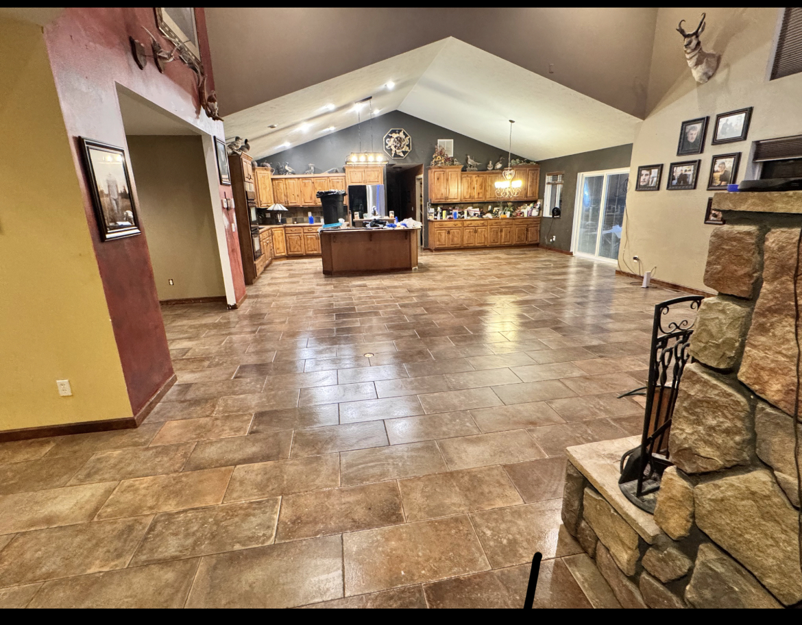 Open-plan kitchen and living room with full tile floor and stone fireplace, installed by Five Tiles