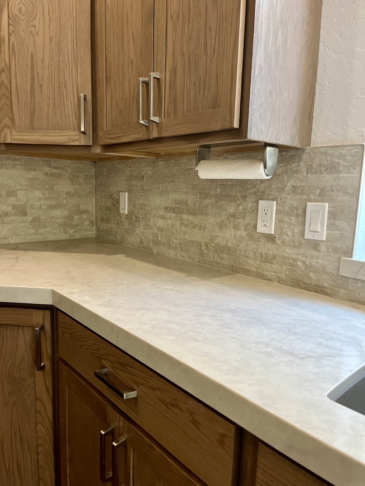 Kitchen corner with stone backsplash and light quartz countertop